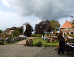 Ondanks dreigende wolken blijft het droog. Bezoekers koesteren zich in het zonnetje.